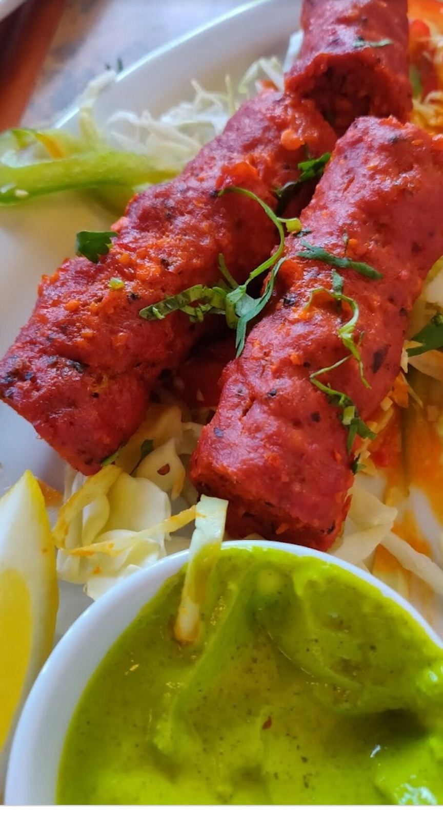 Seekh kebabs on shredded cabbage with green chutney